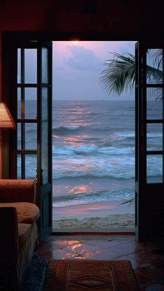 an open door leading to the ocean at sunset with palm trees in the foreground