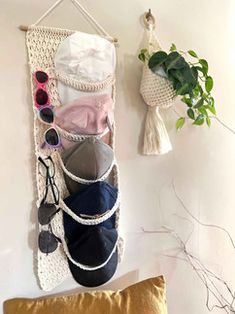 a wall hanging with shoes and other items on it next to a pillow, potted plant