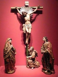 the crucifix is on display in front of a red wall with other statues