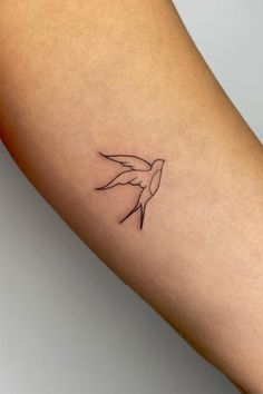 a small tattoo on the arm of a woman with a bird in it's beak