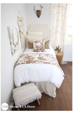 a white bed sitting in a bedroom next to a wall mounted antelope head