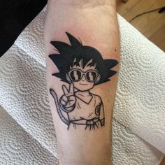 a person with a tattoo on their arm that has a drawing of a cartoon character holding a peace sign