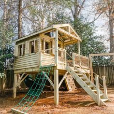 a wooden play structure with a slide and climbing rope