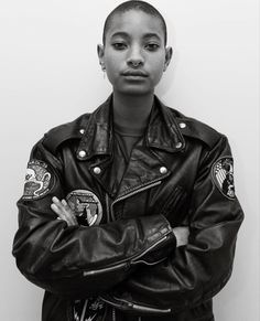 a black and white photo of a woman in a leather jacket with her arms crossed