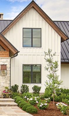 a white house with black roof and stone steps leading up to the front door area