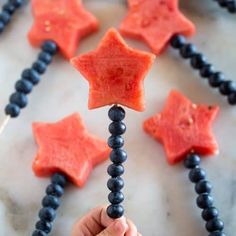 a child's hand reaching for some food on a beaded necklace with red and blue stars