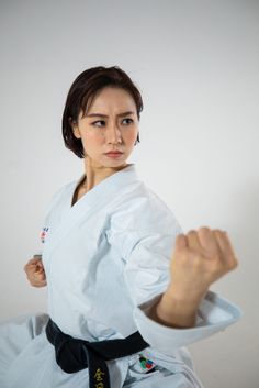 a woman in a white kimono is posing for the camera with her fist raised