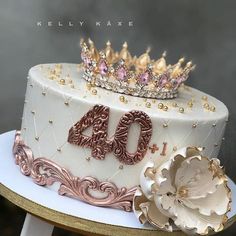 a white cake with gold decorations and a crown on top that says 40 years old