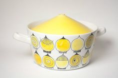 a yellow and white bowl with an artistic design on the bottom, sitting on a white surface