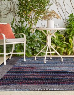 two chairs and a table with plants in the background