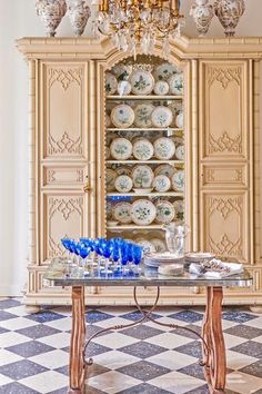 a dining room table with blue and white dishes on it, in front of a china cabinet