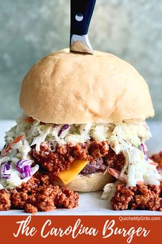 a close up of a sandwich with meat and coleslaw on it, with a knife stuck in the bun