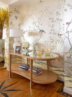 a table with two vases on it in front of a wallpapered room