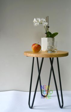 a table with an apple and vase on it next to a white flower in a pot