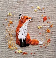 an embroidered picture of a fox sitting on the ground