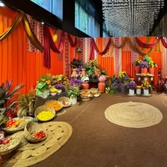 a room filled with lots of different types of flowers and plants on the floor next to an orange wall