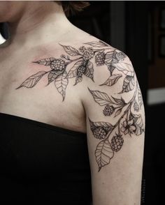 a woman's shoulder with flowers and leaves on it