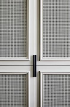 two white doors with black handles on each side and one door has mesh panels in the middle