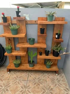 several wooden shelves filled with potted plants on top of a tiled floor next to a wall