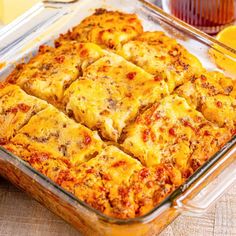 a casserole dish with cheese and meat in it on a wooden table next to orange juice