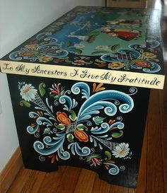 a wooden box with painted designs on the lid and bottom, sitting on top of a hard wood floor