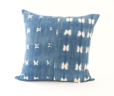 a blue and white tie - dyed pillow with bows on the front, sitting on a white surface