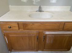 a bathroom sink sitting under a mirror on top of a wooden cabinetry next to a wall