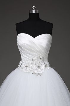 a white wedding dress on a mannequin with flowers in the front and bottom