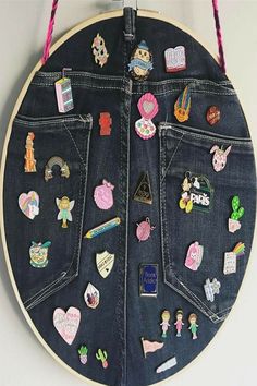 the back side of a denim jacket with patches and pins attached to it, hanging on a wall