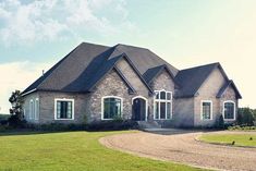 a large brick house sitting on top of a lush green field next to a dirt road