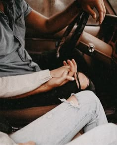 two people sitting in a car with their hands on the steering wheel