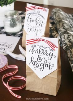 two paper bags with candy canes and tags on them sitting on a table next to wrapping