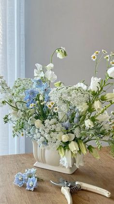 a bouquet of flowers sitting on top of a wooden table next to scissors and pliers