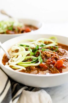 two bowls of soup with noodles, meat and vegetables