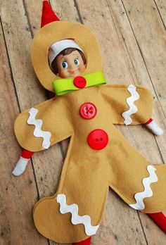 a gingerbread man made out of felt with buttons on his face and legs, sitting on a wooden floor