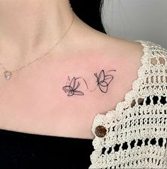 a woman's chest with two small butterflies on the left side of her neck