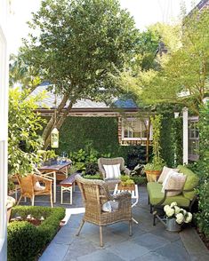 an outdoor living area with chairs, tables and plants on the side of the house