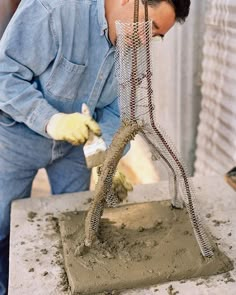 a man working on a piece of art with wire and sand in front of him