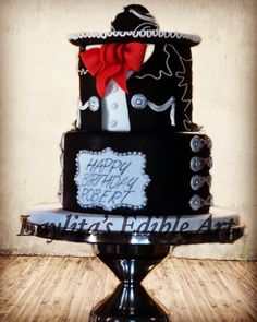 a black and white birthday cake with a red bow