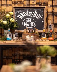 bottles and glasses are sitting on a table in front of a sign that reads whiskey bar old no 40