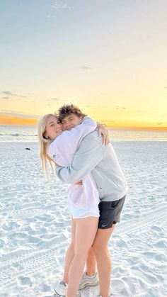 two people hugging each other on the beach