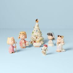 a group of small figurines standing next to each other in front of a christmas tree