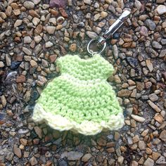 a green and white crochet hat laying on top of rocks next to a pair of scissors