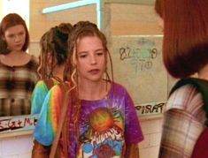 a girl with dreadlocks standing in front of a mirror