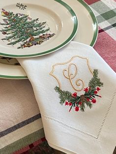 two christmas napkins on top of each other next to a white plate with a green and red design