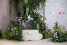 a white couch surrounded by plants and flowers