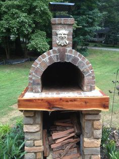 an outdoor brick oven with a lion head on the front and side door is shown