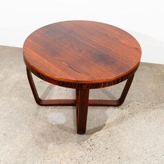 a round wooden table sitting on top of a cement floor