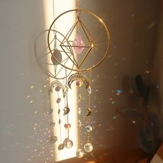 a dream catcher hanging on the wall next to a window with sun shining through it