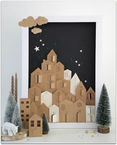 an image of a christmas scene made out of cardboard and cut into small houses with trees in the foreground